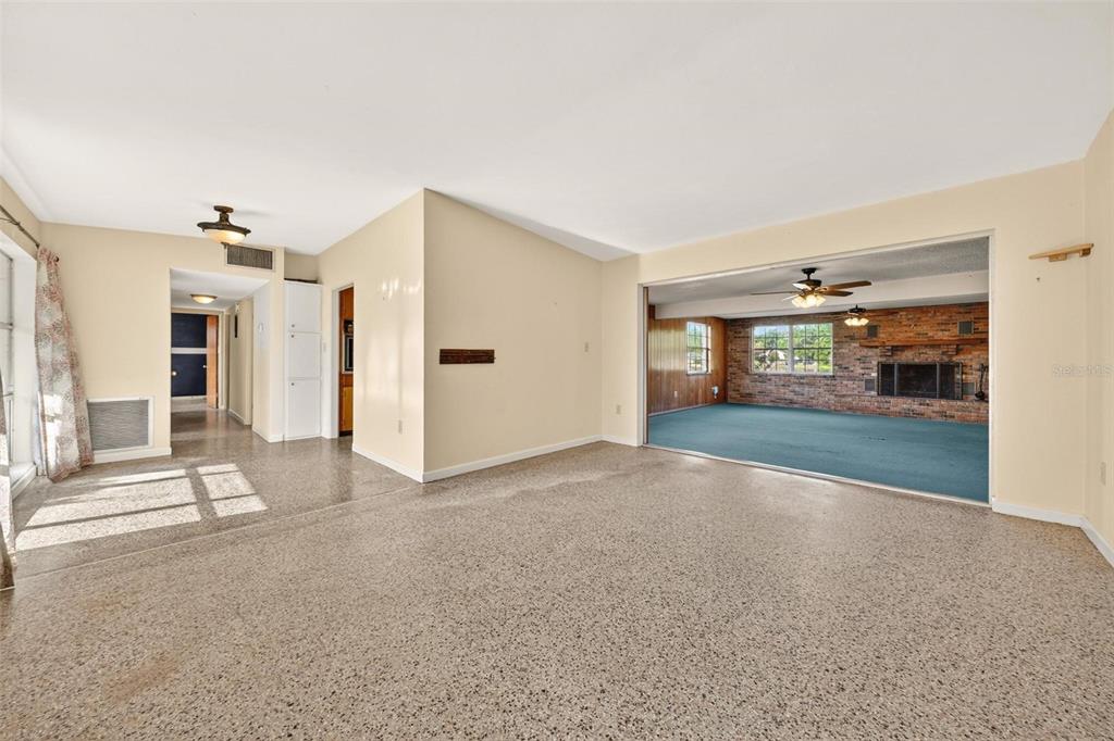A living room with terrazzo flooring connects to a sunken den featuring a brick fireplace — 710 TWIN OAKS LANE, EUSTIS, FL
