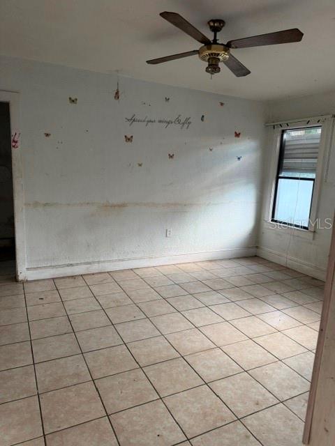 An empty room features tiled floors, a ceiling fan, and a wall with butterfly decals — 1607 CENTER STREET, LEESBURG, FL