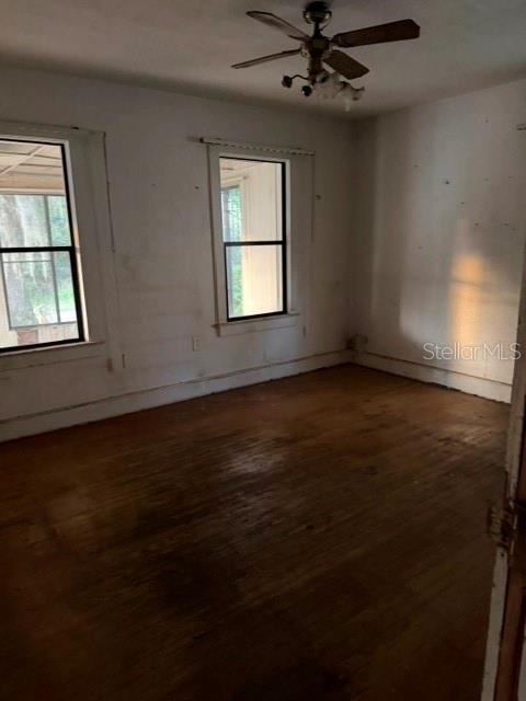 An empty room features hardwood floors, two windows, and a ceiling fan — 1607 CENTER STREET, LEESBURG, FL