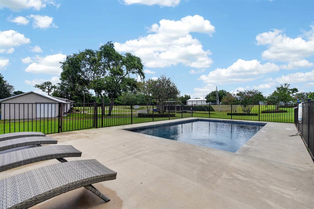 A fenced swimming pool with lounge chairs on a concrete deck near a house — 350 FOX HOLLOW FARMS ROAD, PIERSON, FL
