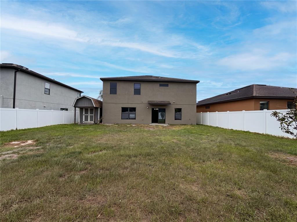 The backyard of a two-story house features a small shed and white vinyl fencing — 14207 ALISTAR MANOR DRIVE, WIMAUMA, FL