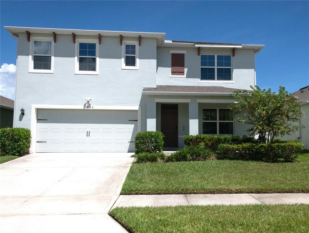 A two-story light blue house features a two-car garage, a front porch, and landscaping — 3940 SILVERSTREAM TERRACE, SANFORD, FL