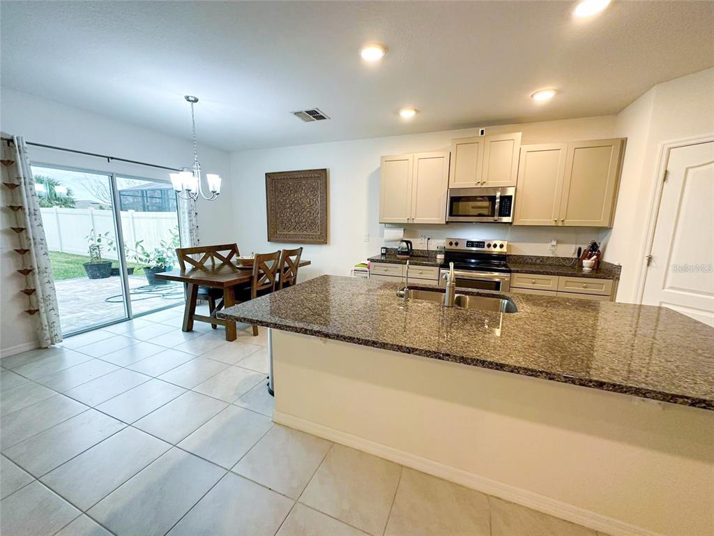 A kitchen with granite countertops and a dining area featuring a sliding glass door — 3940 SILVERSTREAM TERRACE, SANFORD, FL