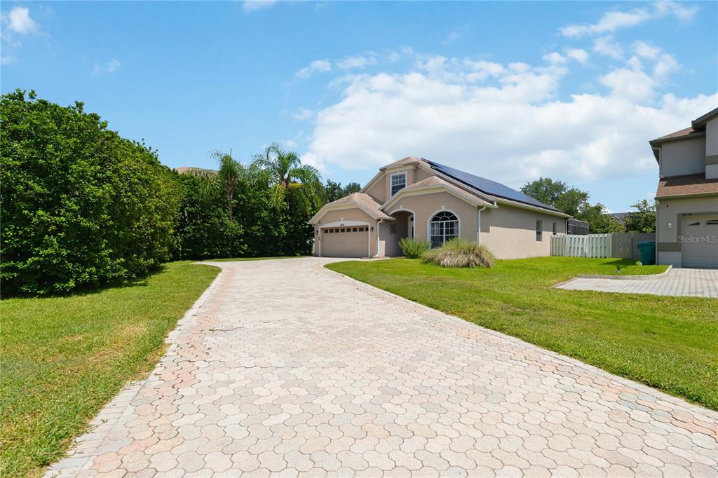 A single-story house with a paved driveway, solar panels, and a large green hedge — 6658 LAKE PEMBROKE PLACE, ORLANDO, FL
