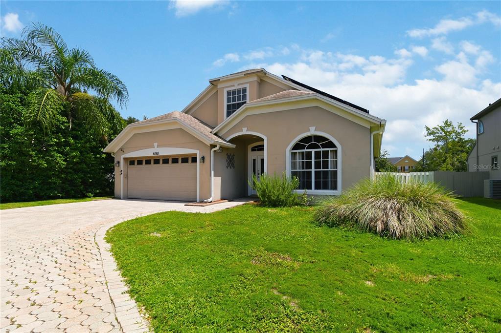 A single-story house with a beige stucco exterior, a two-car garage, and a paved driveway — 6658 LAKE PEMBROKE PLACE, ORLANDO, FL