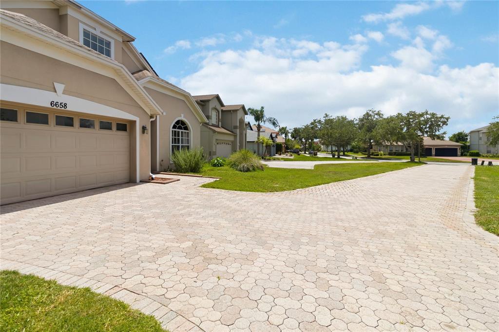 A beige house with a paved driveway and a two-car garage under a blue sky — 6658 LAKE PEMBROKE PLACE, ORLANDO, FL
