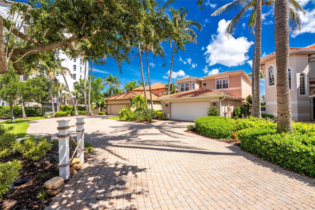 A paved driveway leads to a two-story house with a garage and palm trees — 3341 SUNSET KEY CIRCLE, PUNTA GORDA, FL