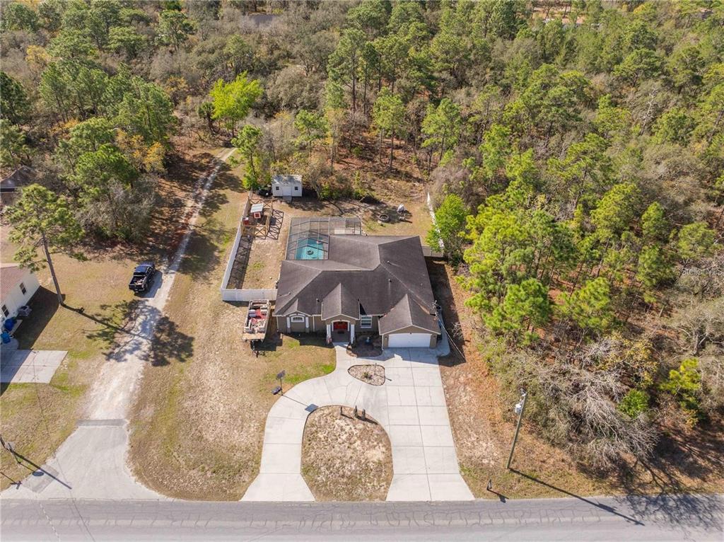 An aerial view shows a single-story house with a pool cage and a circular driveway — 13040 QUIGLEY AVENUE, WEEKI WACHEE, FL