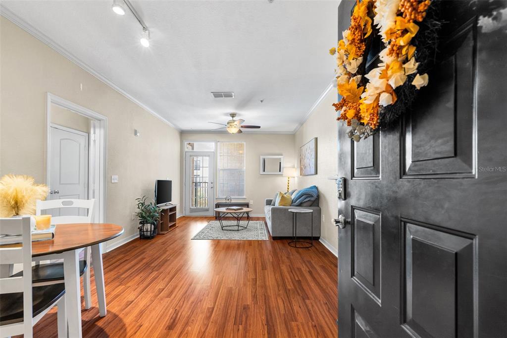 An empty living room features tan walls, wood-look flooring, a ceiling fan, and a glass door — 4221 W SPRUCE STREET UNIT 1310, TAMPA, FL