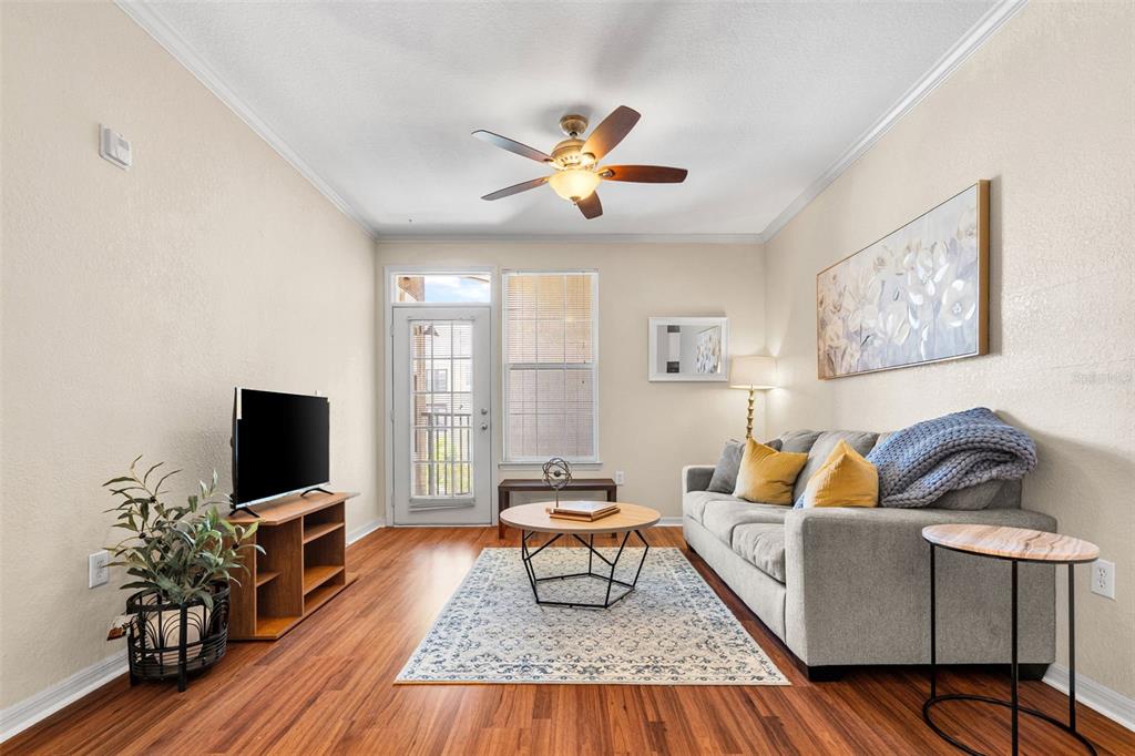 An open living area features wood-look flooring, a ceiling fan, and an adjacent kitchen — 4221 W SPRUCE STREET UNIT 1310, TAMPA, FL