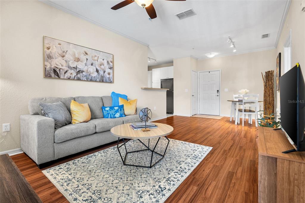 An empty living room features wood-look flooring, tan walls, a ceiling fan, and an entryway — 4221 W SPRUCE STREET UNIT 1310, TAMPA, FL