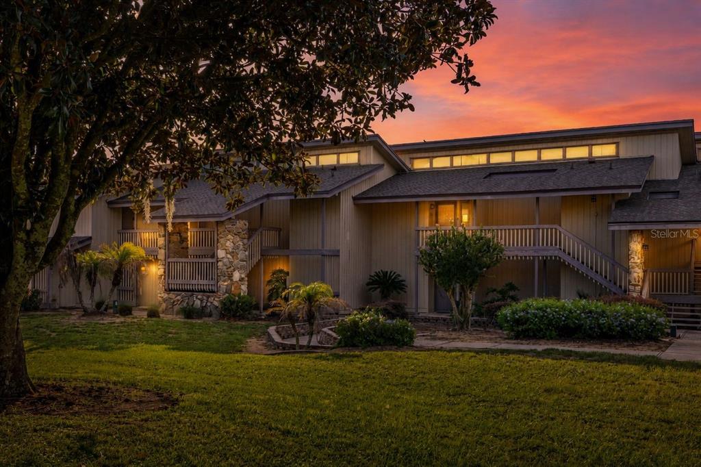 A two-story apartment building exterior features wooden siding, stone accents, and a sunset sky — 2272 BURNWAY ROAD UNIT 2272, HAINES CITY, FL