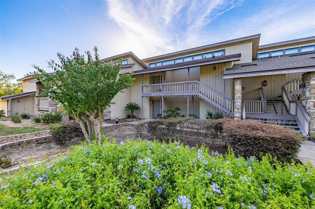 Exterior view of a multi-story apartment building with wooden siding, stairs, and landscaped grounds — 2272 BURNWAY ROAD UNIT 2272, HAINES CITY, FL