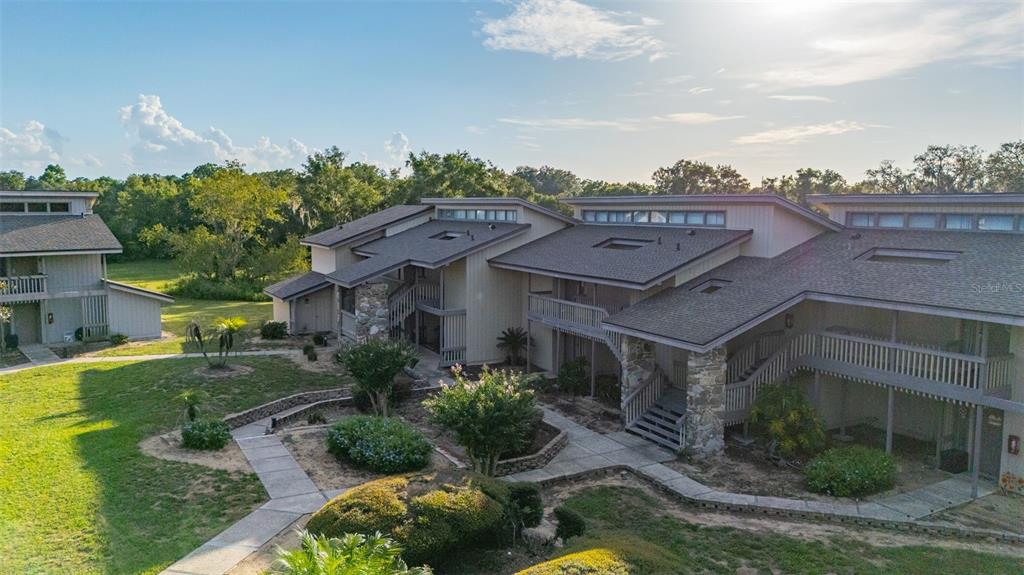An aerial view of a multi-unit residential building with wooden siding and stone accents — 2272 BURNWAY ROAD UNIT 2272, HAINES CITY, FL