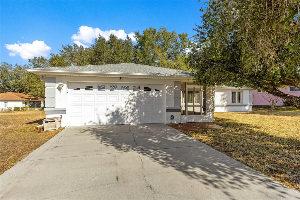 A single-story house with a white garage door, a screened entryway, and a concrete driveway — 6115 SW 104TH STREET, OCALA, FL