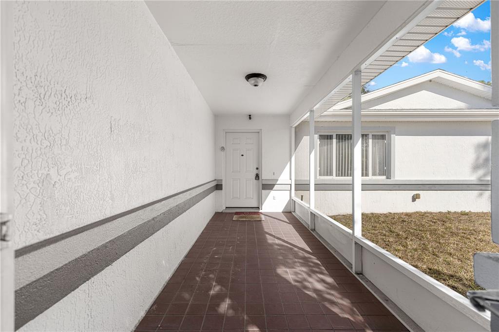 A covered, screened-in front porch with tiled flooring leads to a white front door — 6115 SW 104TH STREET, OCALA, FL