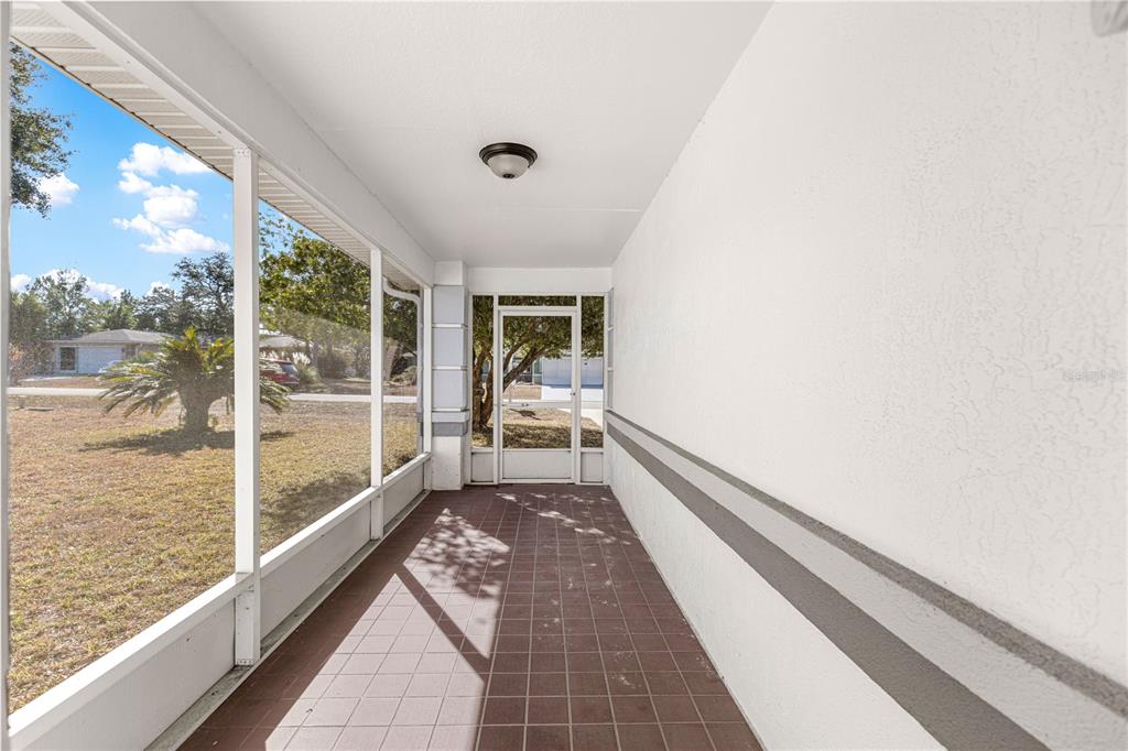 A screened-in porch features tiled flooring, a white ceiling with a light fixture, and exterior views — 6115 SW 104TH STREET, OCALA, FL