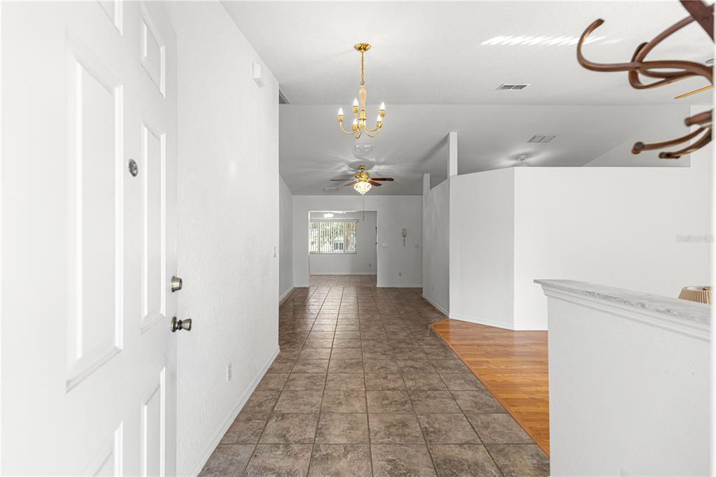 A tiled entryway leads into a living area with white walls and a vaulted ceiling — 6115 SW 104TH STREET, OCALA, FL