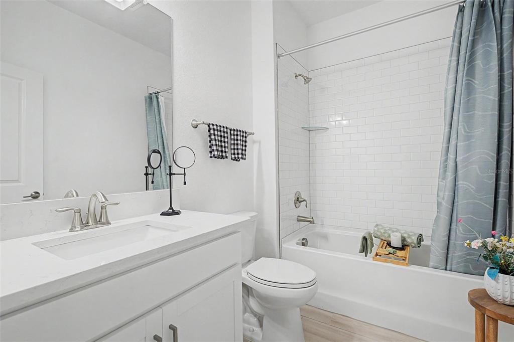 A bathroom features a white vanity, a toilet, and a bathtub with white subway tile — 10499 GABLE DIG LOOP, SAN ANTONIO, FL