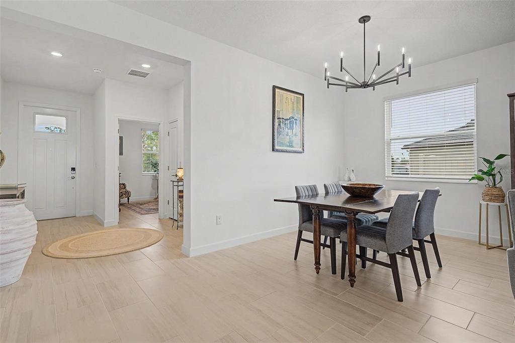 A dining room with a dark wood table, grey chairs, and a modern chandelier — 10499 GABLE DIG LOOP, SAN ANTONIO, FL