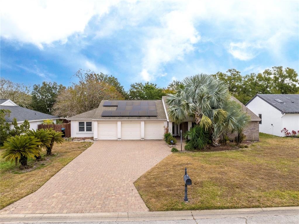 A single-story house with a three-car garage, solar panels, and a paved driveway — 6013 CRYSTAL VIEW DRIVE, ORLANDO, FL