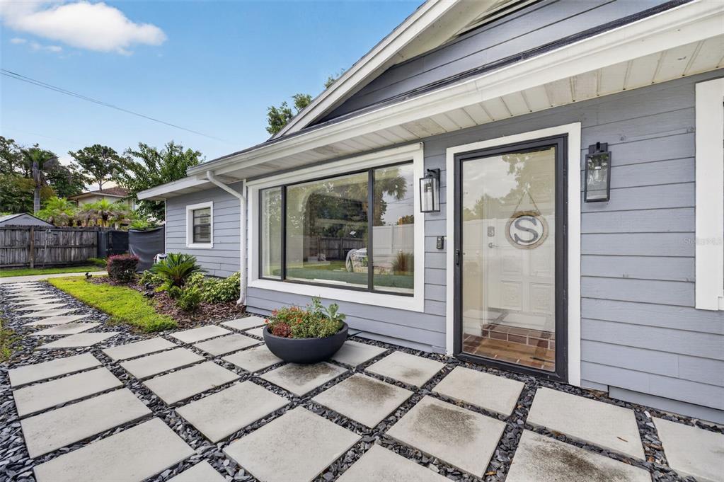 A gray house exterior features a paved patio, a large window, and a glass front door — 790 S LAKE SYBELIA DRIVE, MAITLAND, FL