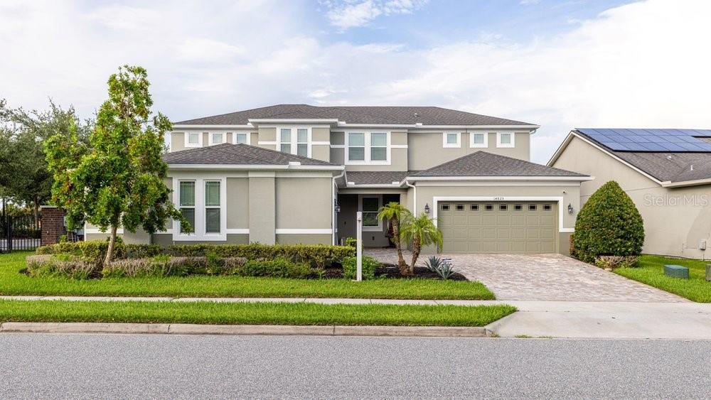 A two-story suburban house with a light-colored exterior, a paved driveway, and a garage — 14825 ELLINGSWORTH LANE, WINTER GARDEN, FL