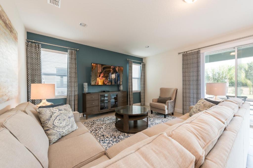 A living room features a blue accent wall, a television, and a large sectional sofa — 7467 MARKER AVE, KISSIMMEE, FL