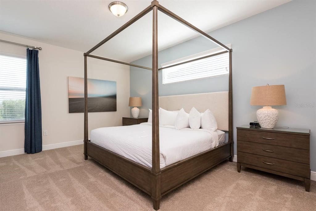 A bedroom features a wooden canopy bed, two nightstands with lamps, and blue accent walls — 7467 MARKER AVE, KISSIMMEE, FL