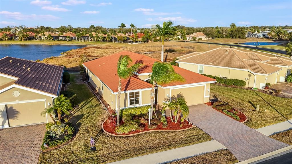An aerial view shows a single-story house with a red tile roof and paved driveway — 7486 TALON BAY DRIVE, NORTH PORT, FL