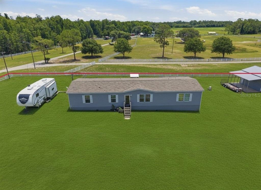 The exterior of a light gray manufactured home features a wooden staircase and fenced yard — 7242 BLACK ROAD, LAKE WALES, FL