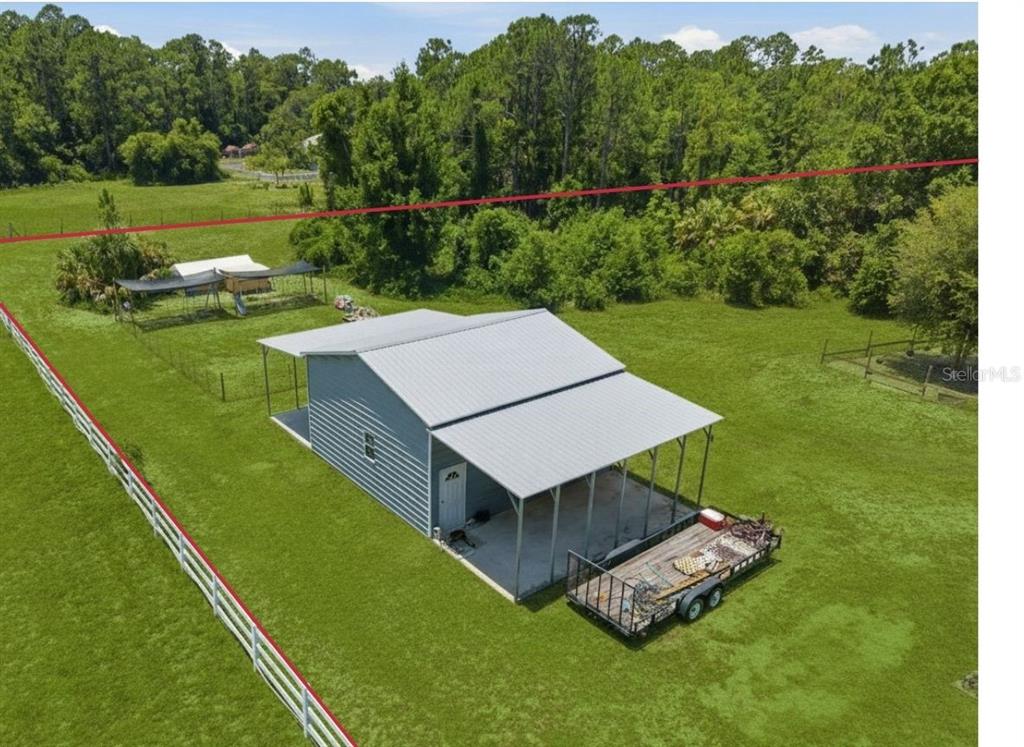 A detached metal garage with two open-sided carports sits on a large grassy lawn — 7242 BLACK ROAD, LAKE WALES, FL