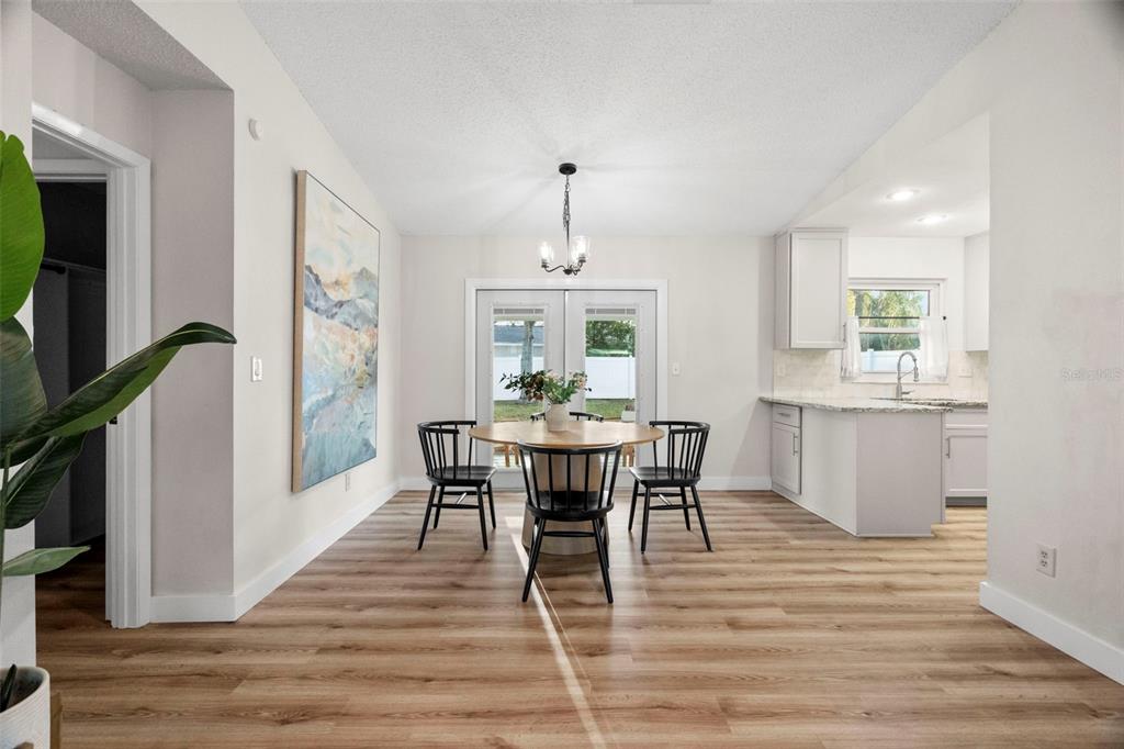 A dining area features a round wooden table, black chairs, and light wood-look flooring — 6500 BRIAR RIDGE COURT N, PINELLAS PARK, FL