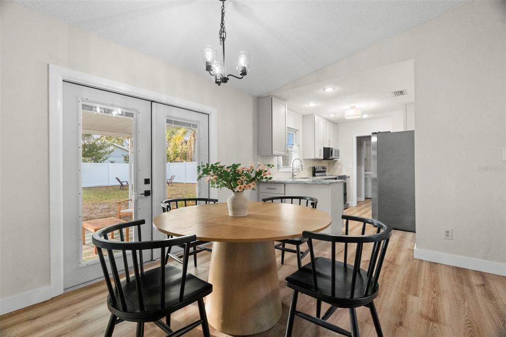 A dining area with a round wooden table, black chairs, and a view of the backyard — 6500 BRIAR RIDGE COURT N, PINELLAS PARK, FL