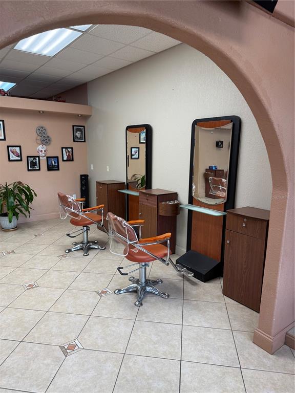 A hair salon features two styling stations with mirrors, chairs, and wooden cabinets on tiled floors — 500 W GRANADA BOULEVARD UNIT 3, ORMOND BEACH, FL