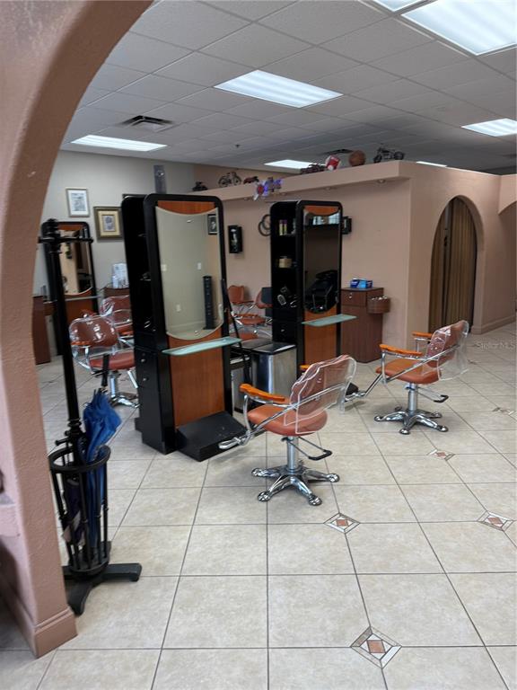 A hair salon features two styling stations with mirrors, orange chairs, and tiled flooring — 500 W GRANADA BOULEVARD UNIT 3, ORMOND BEACH, FL