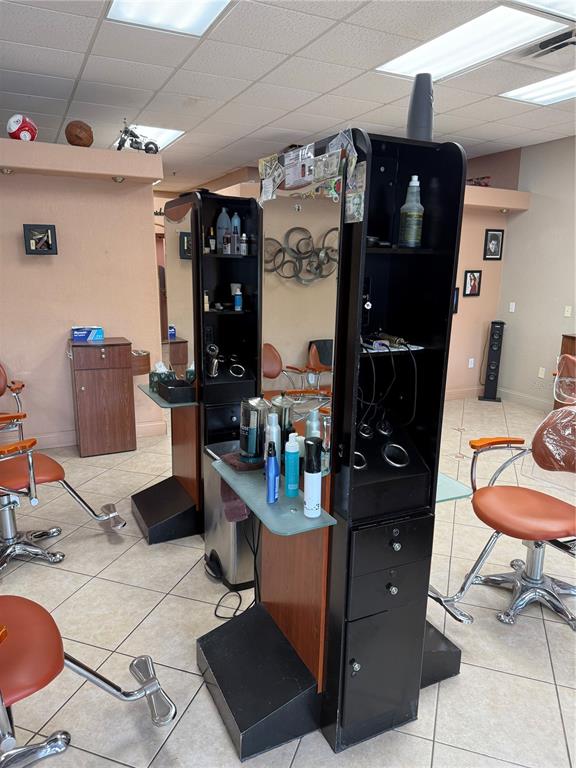 A hair salon features two double-sided styling stations with mirrors, orange chairs, and tile flooring — 500 W GRANADA BOULEVARD UNIT 3, ORMOND BEACH, FL