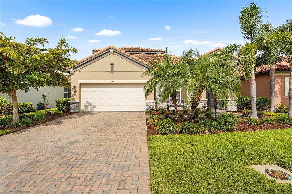 A single-story house with a paved driveway, a two-car garage, and palm trees — 2745 62ND AVENUE E, ELLENTON, FL