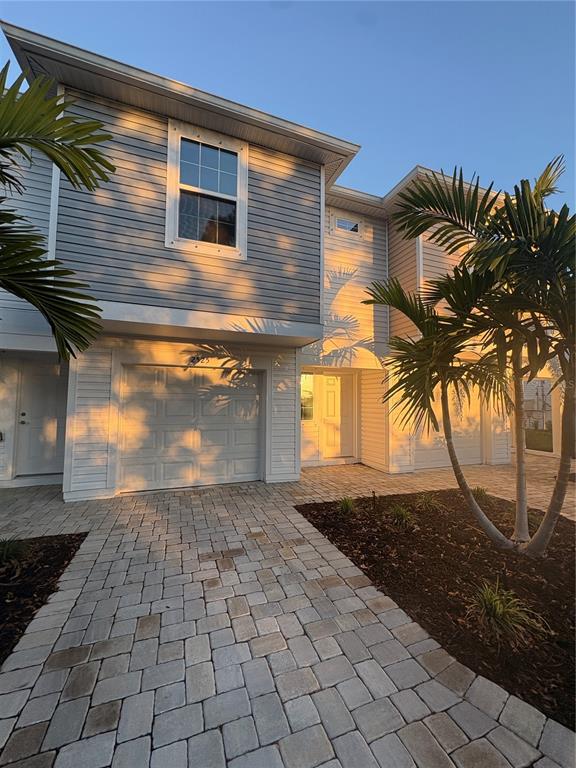 A two-story townhouse exterior with gray siding, a garage, and a paver driveway at sunset — 2525 6TH AVENUE DRIVE E, BRADENTON, FL