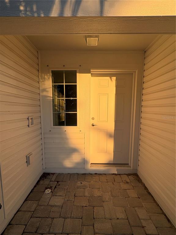 A paved entryway features a white door, a window, and light-colored horizontal siding — 2525 6TH AVENUE DRIVE E, BRADENTON, FL
