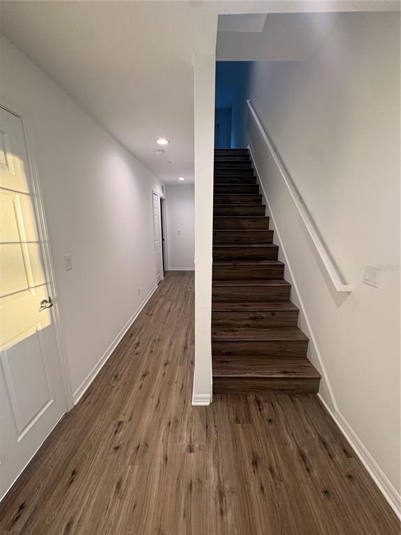 A hallway with wood-look flooring leads to a staircase with dark wood treads — 2525 6TH AVENUE DRIVE E, BRADENTON, FL