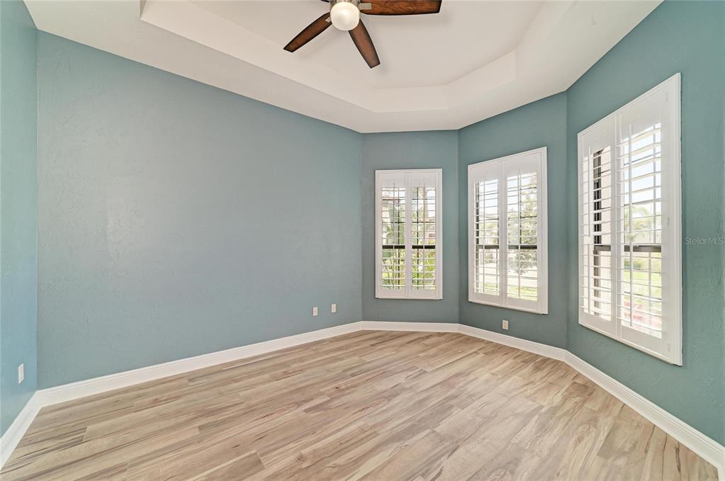 An empty room with blue walls, a tray ceiling, and light-colored wood-look flooring — 5819 TITLE ROW DRIVE, BRADENTON, FL