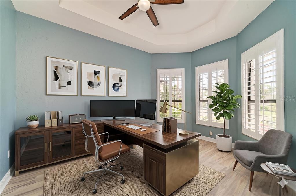 A home office with a wooden desk, brown leather chair, and blue walls — 5819 TITLE ROW DRIVE, BRADENTON, FL