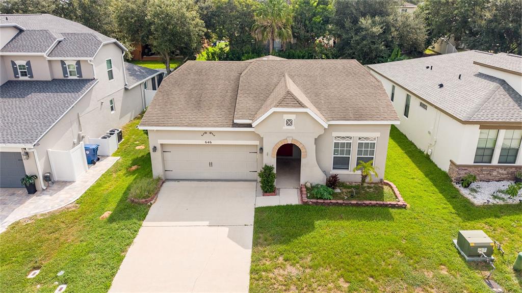 An aerial view of a single-story suburban house with a tan stucco exterior and garage — 646 ARBOR POINTE AVENUE, MINNEOLA, FL