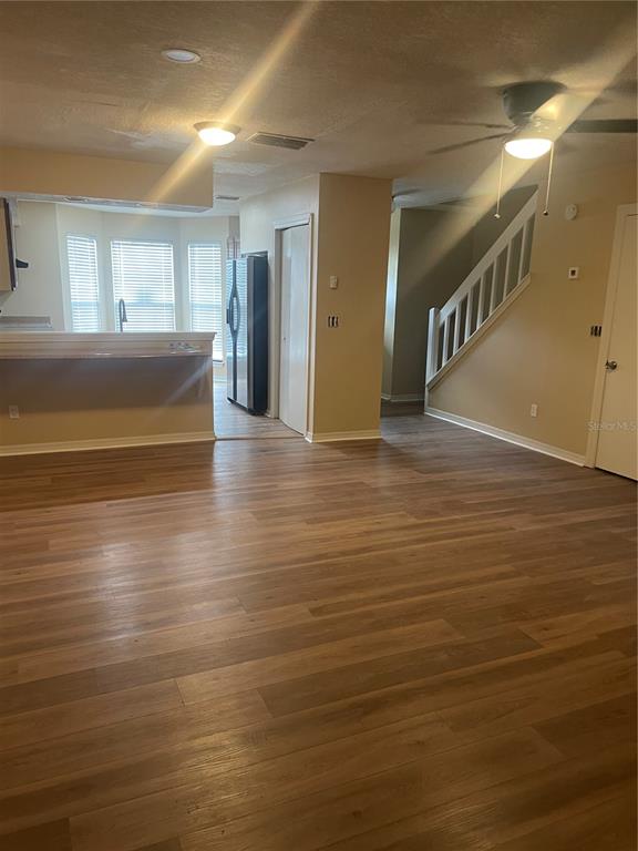 An open living area with wood-look flooring, a kitchen counter, and a staircase — 5565 N CABOT DRIVE, JACKSONVILLE, FL