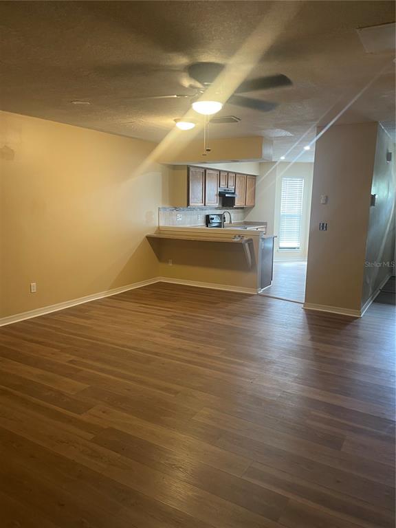 A living area with wood-look flooring opens to a kitchen featuring a breakfast bar — 5565 N CABOT DRIVE, JACKSONVILLE, FL
