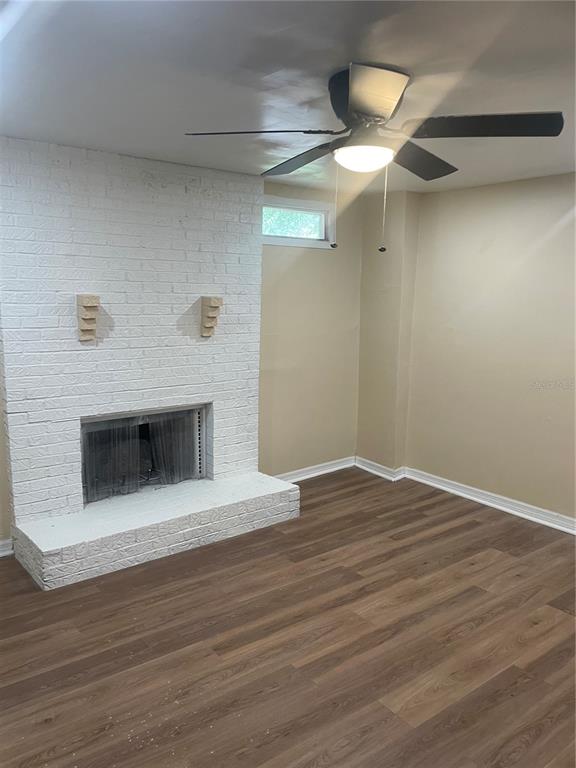 A room features a white painted brick fireplace, wood-look flooring, and a ceiling fan — 5565 N CABOT DRIVE, JACKSONVILLE, FL