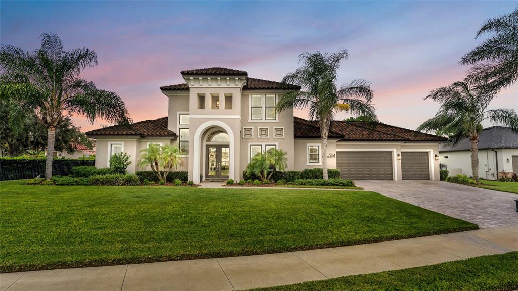A two-story suburban house with a tiled roof, arched entryway, and a three-car garage — 534 BLUE FLAG DRIVE, AUBURNDALE, FL
