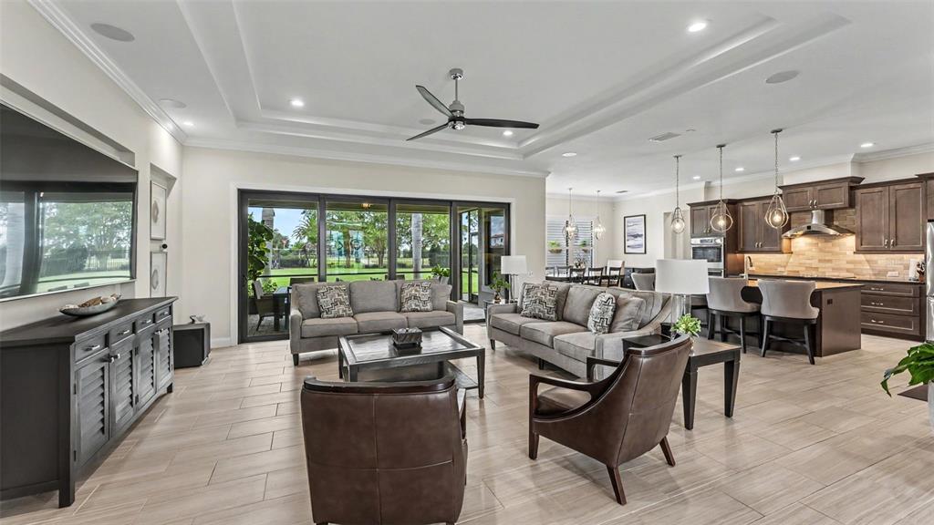 A living room with gray sofas, leather chairs, and a kitchen visible in the background — 534 BLUE FLAG DRIVE, AUBURNDALE, FL