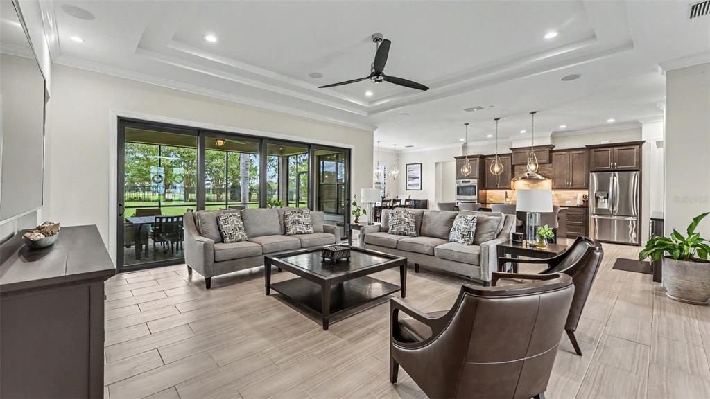 A living room with gray sofas, leather chairs, and a kitchen visible in the background — 534 BLUE FLAG DRIVE, AUBURNDALE, FL
